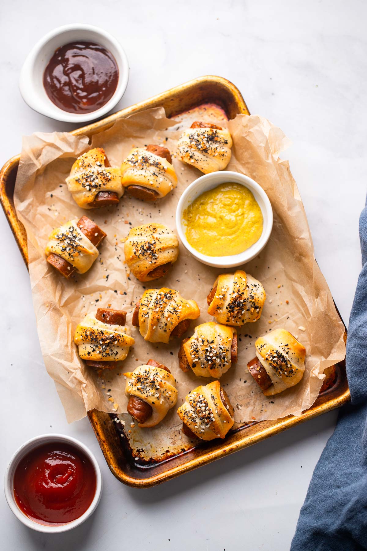 vegan pigs in a blanket on a parchment lined baking sheet with small dish of mustard.
