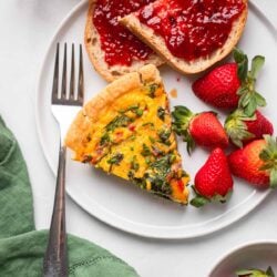 slice of vegan spinach quiche with just egg on a plate with strawberries.