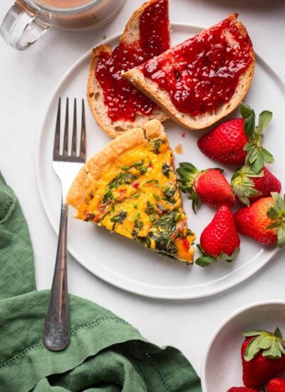 slice of vegan spinach quiche with just egg on a plate with strawberries.