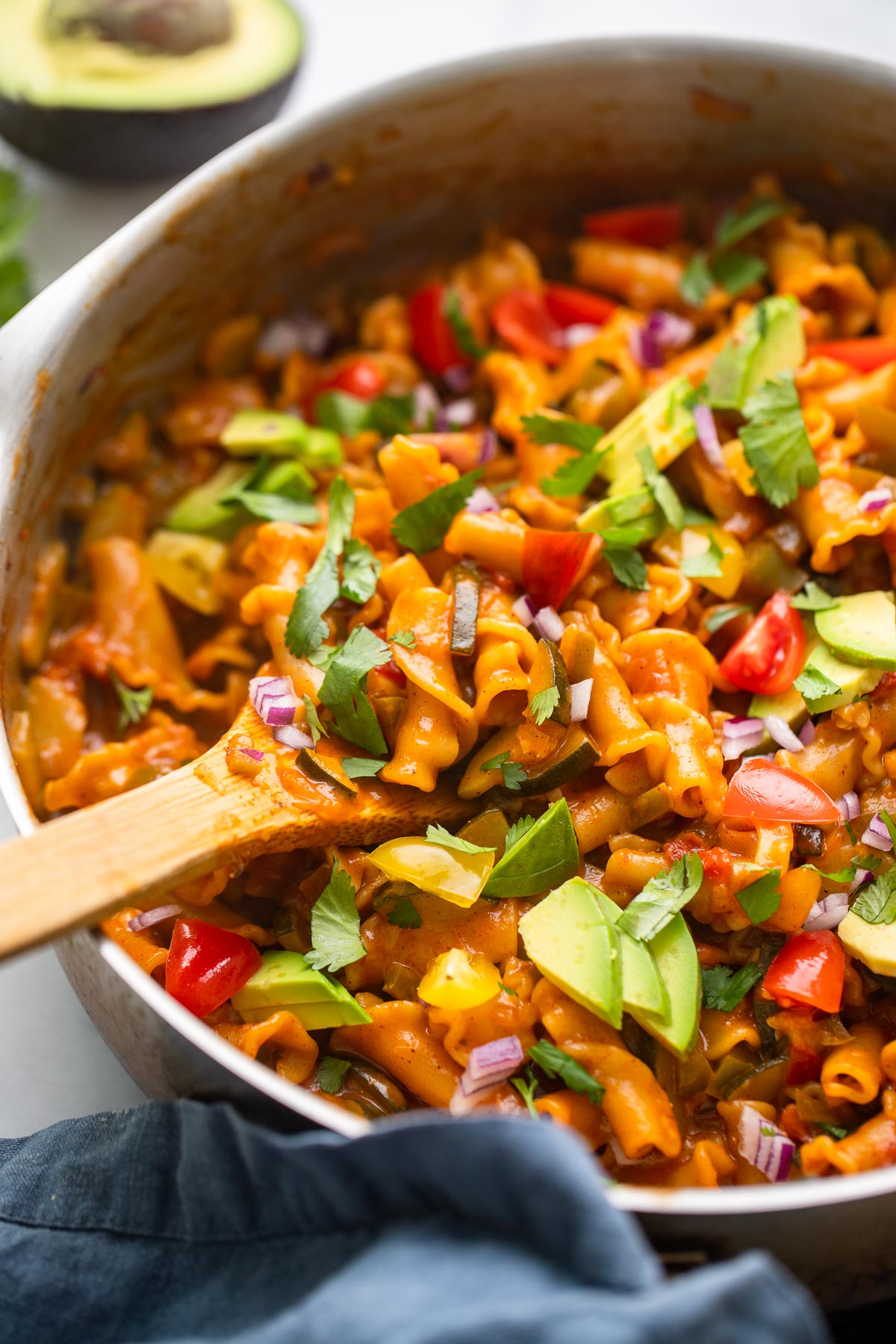 vegan taco pasta in skillet garnished with sliced avocado and fresh cilantro.