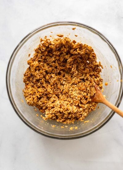 peanut butter granola oat mixture in mixing bowl with a wooden spoon. 
