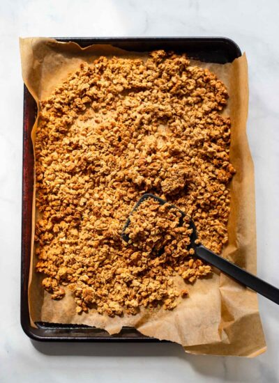 Baked peanut butter granola on a parchment paper lined baking sheet.
