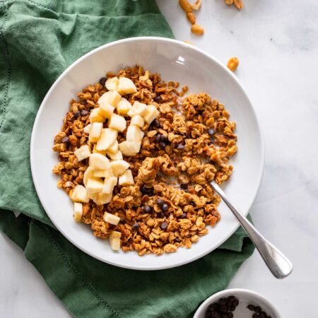 peanut butter granola in a bowl with chopped banana.