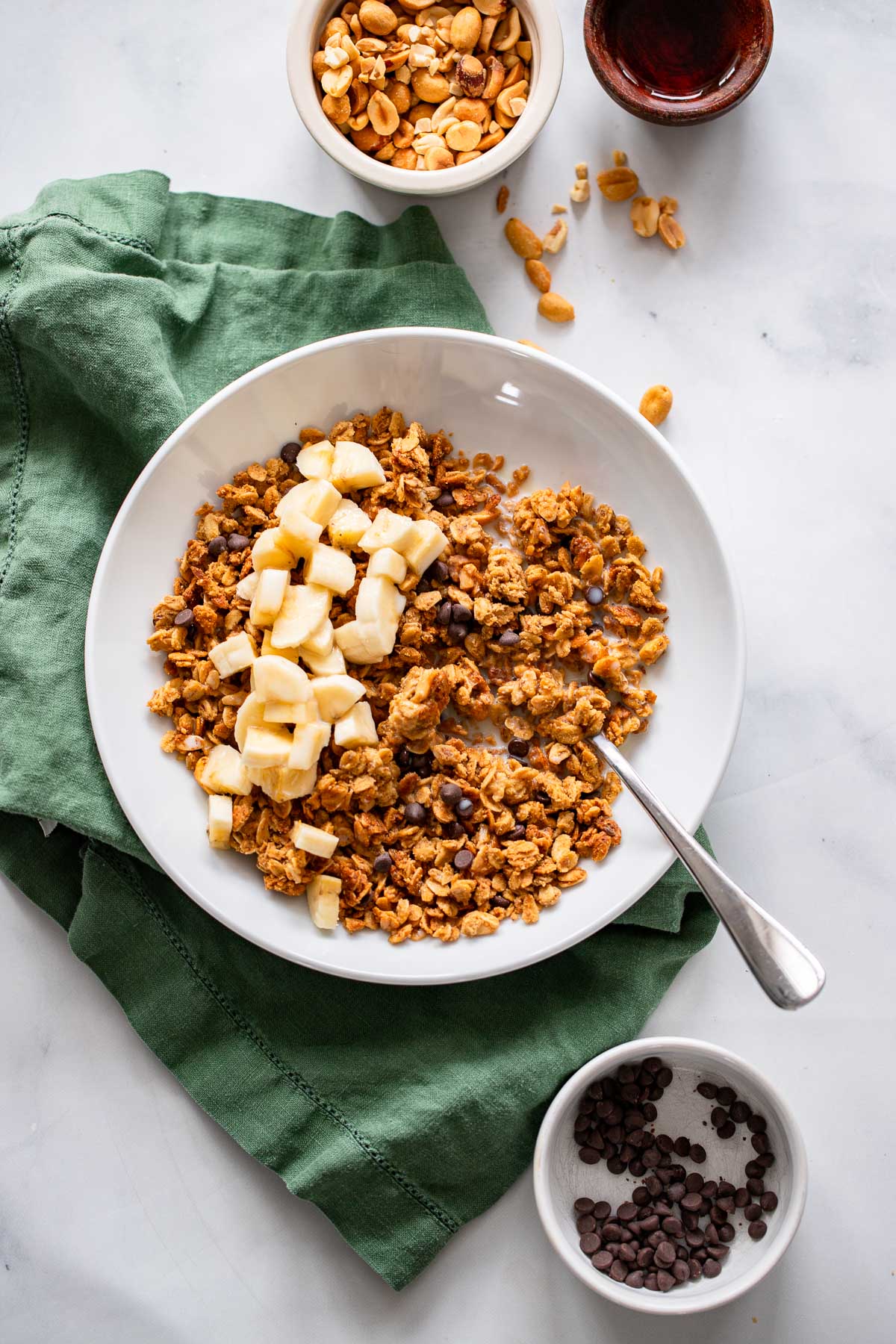 peanut butter granola with chopped bananas and milk in a white bowl. 