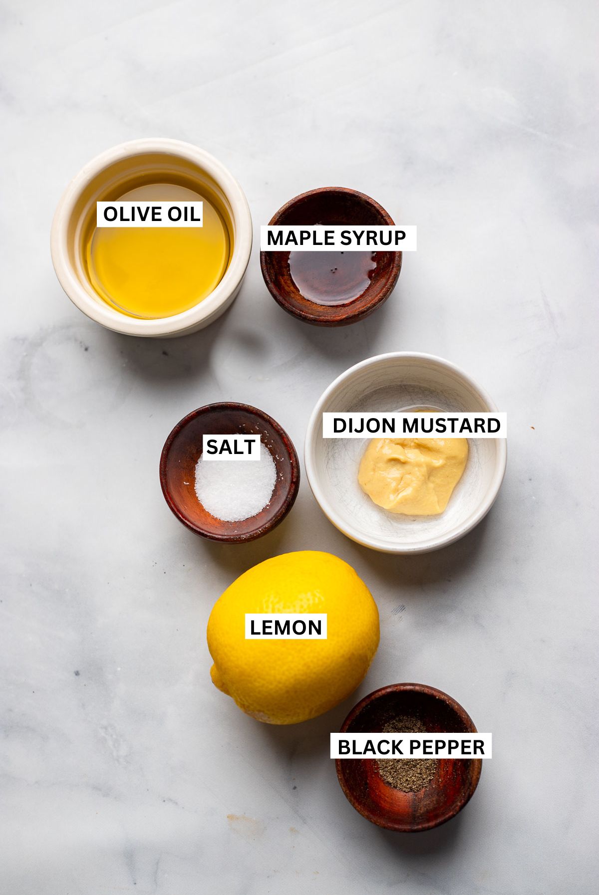 lemon dijon dressing ingredients in small bowls on a white background. 