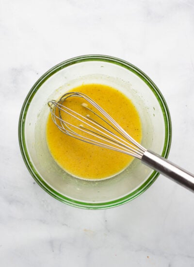 lemon dijon dressing in a bowl with a whisk. 