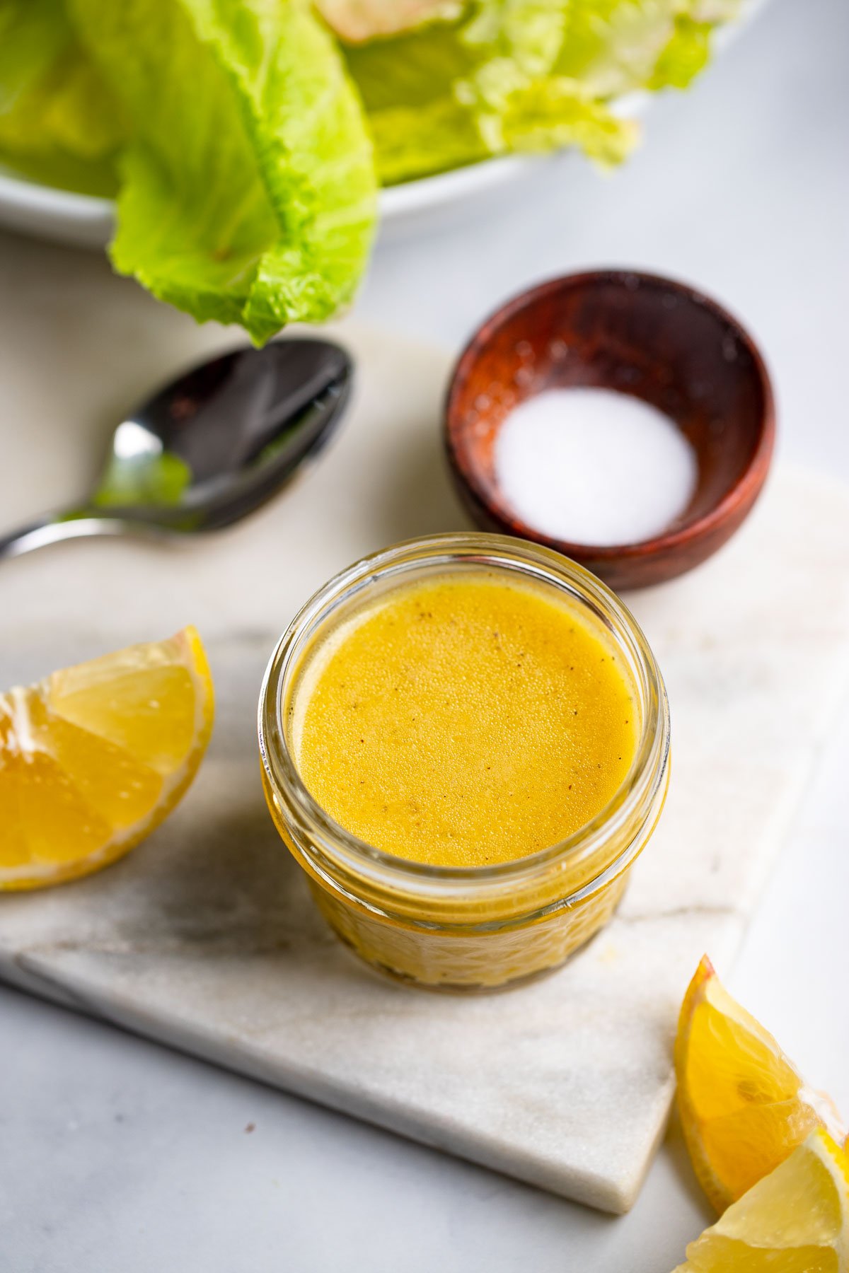 lemon dijon dressing in a small mason jar on a white background. 