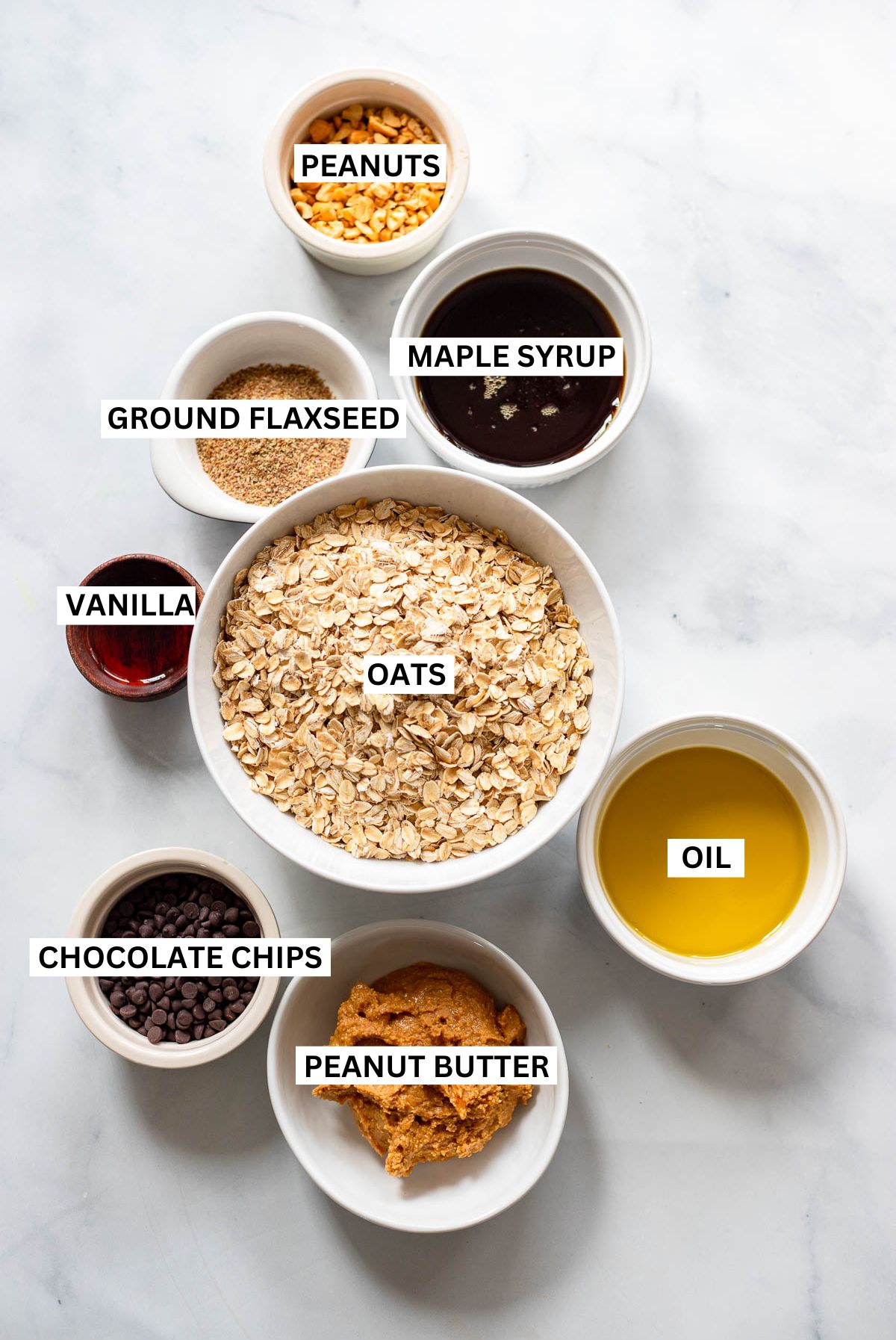 Peanut butter granola ingredients in small bowls with text labels overlaid.