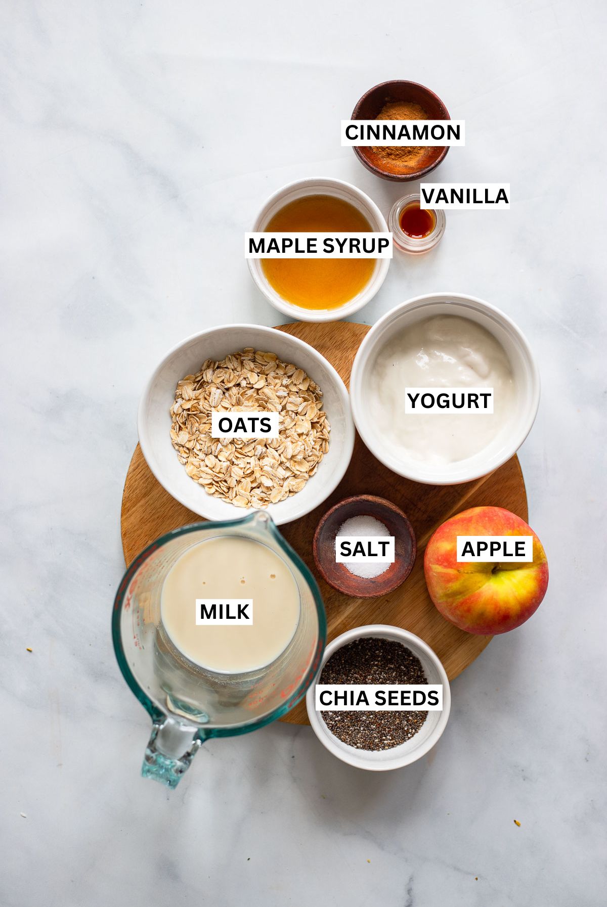 apple cinnamon overnight oats ingredients in small bowls with text overlay labels.