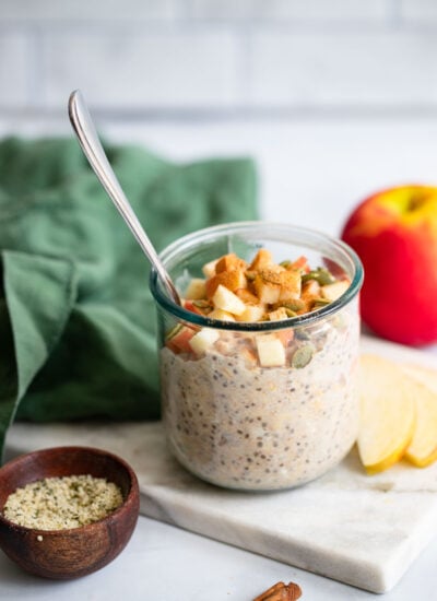 apple cinnamon overnight oats in a glass topped with chopped apple and cinnamon.