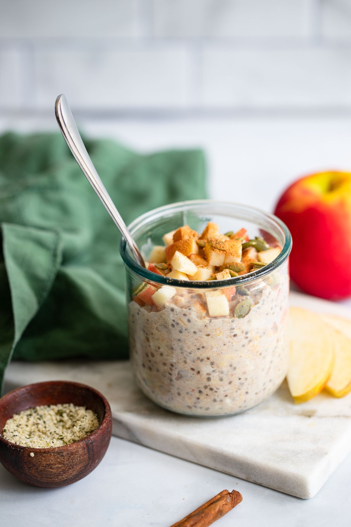 apple cinnamon overnight oats garnished with chopped apple in a glass jar with a spoon.