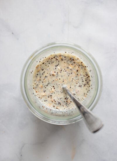 overnight oats ingredients in glass stirred with a spoon.