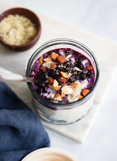 blueberry overnight oats topped with chopped almonds in a glass with a spoon.