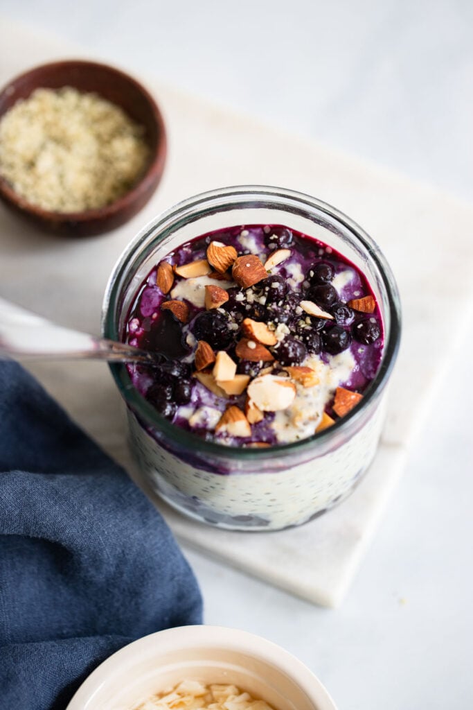 blueberry overnight oats topped with chopped almonds in a glass with a spoon.