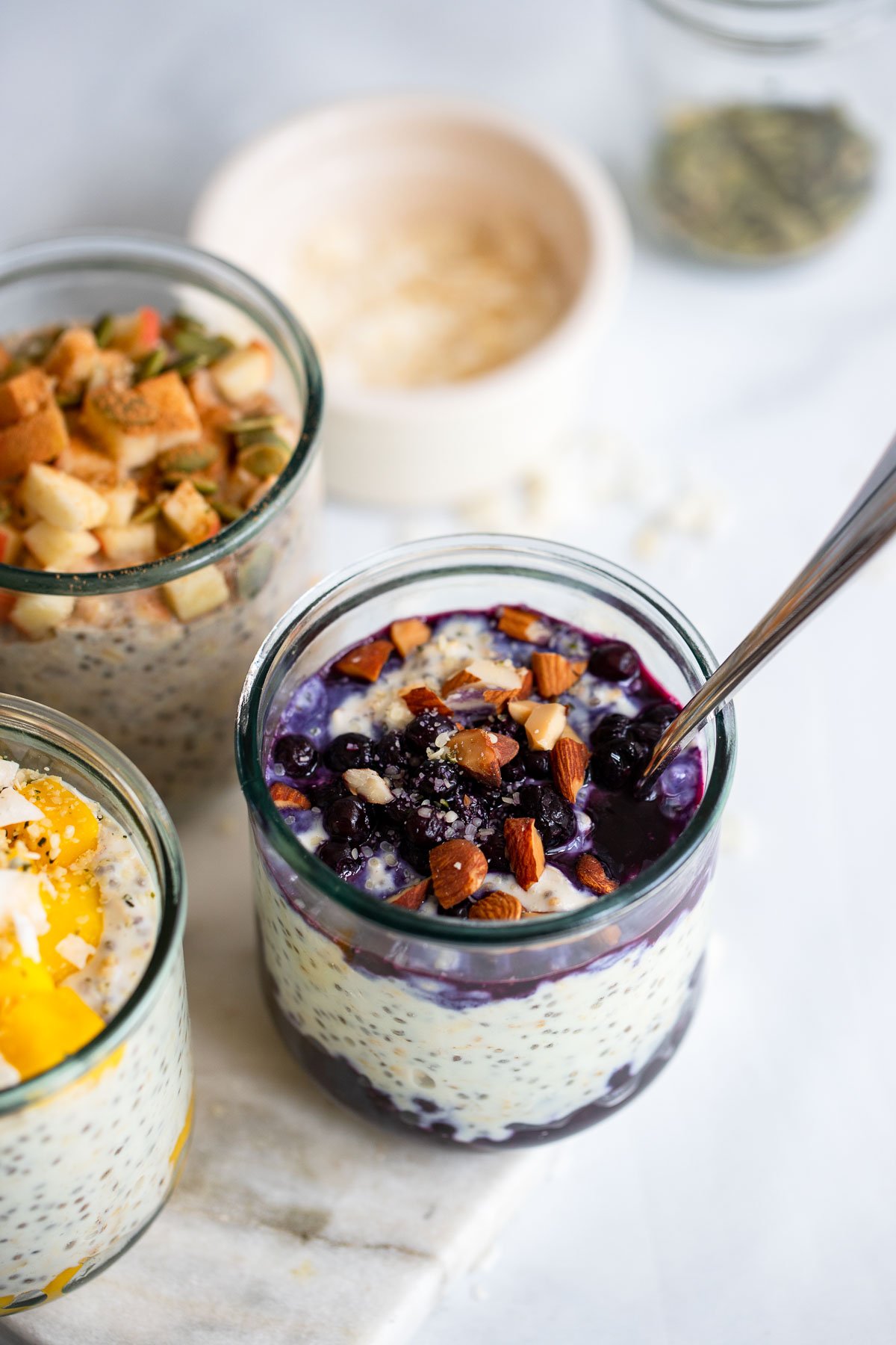 blueberry overnight oats topped with chopped almonds in a glass jar with a spoon.
