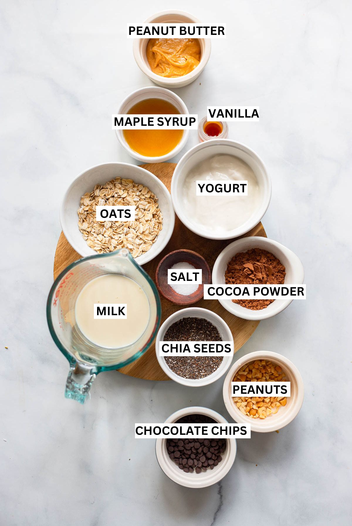 chocolate peanut butter overnight oats ingredients in small bowls on a white background with text overlay labels.