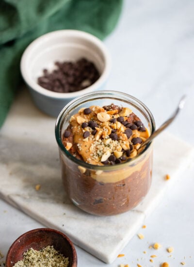 chocolate pb overnight oats in a glass topped with chocolate chips and chopped peanuts.