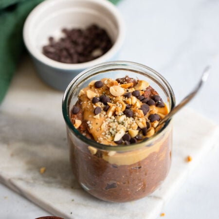 chocolate peanut butter overnight oats in a glass jar with a spoon.