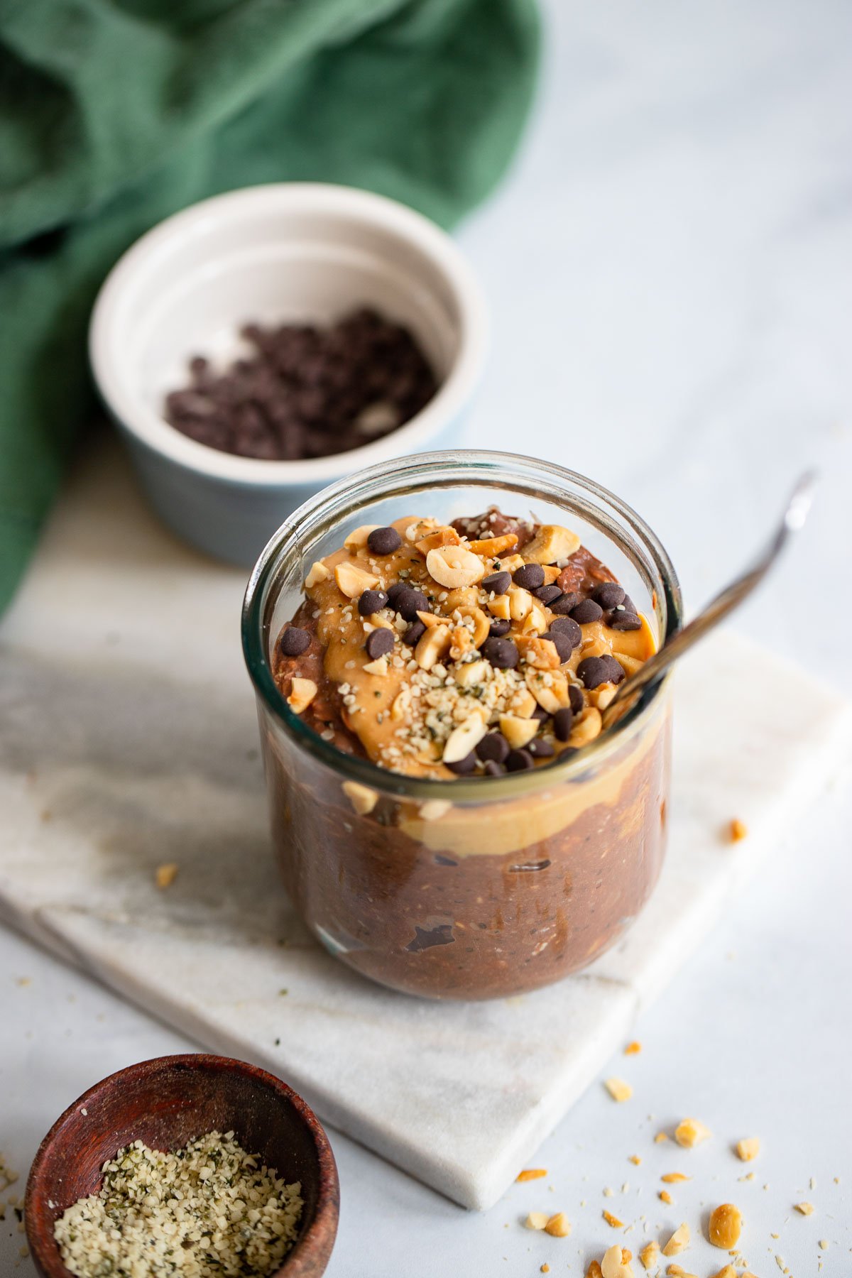 chocolate peanut butter overnight oats topped with chopped peanuts in a glass with a spoon.