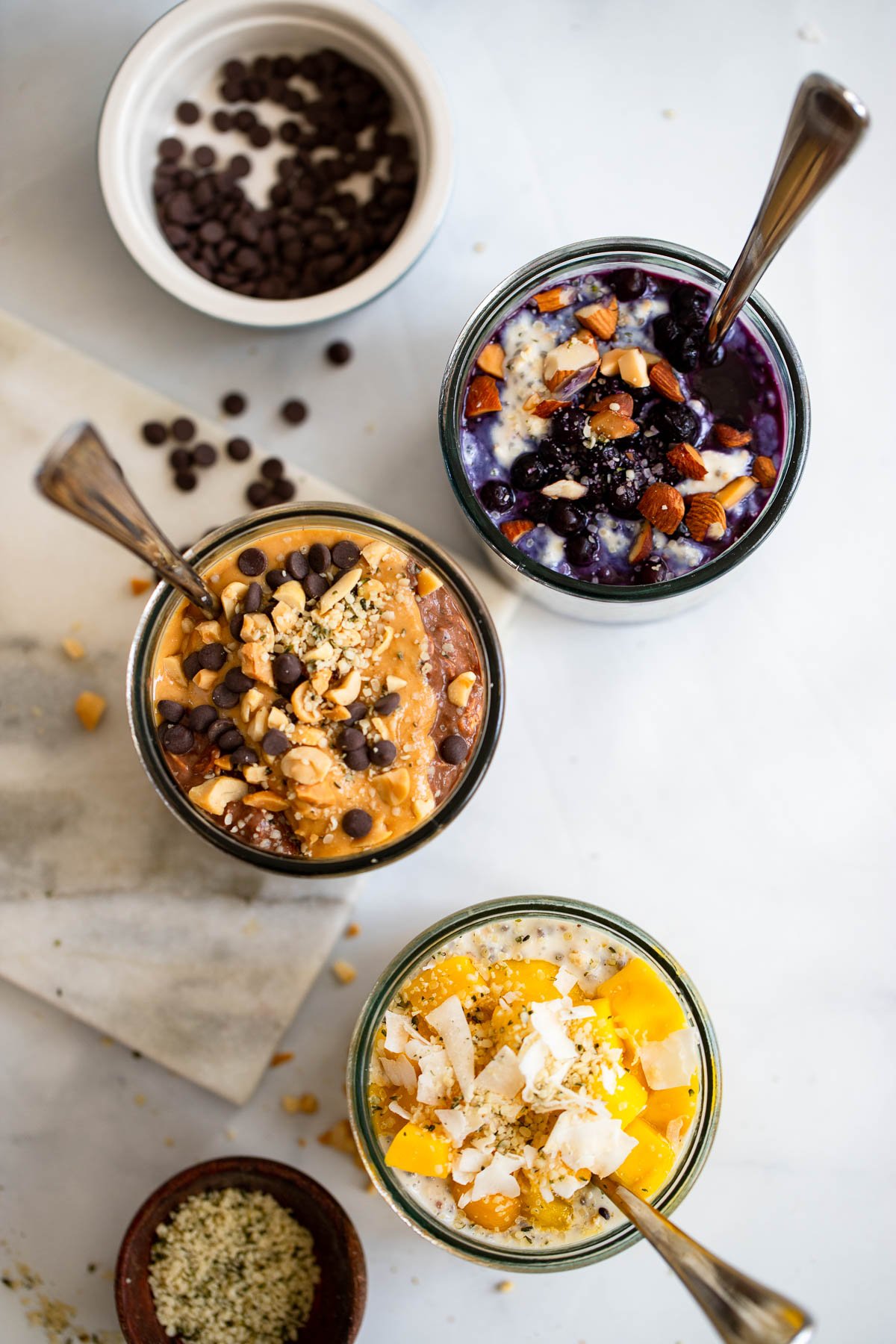 3 glasses full of different flavors of vegan overnight oats with the chocolate peanut butter one in the center.