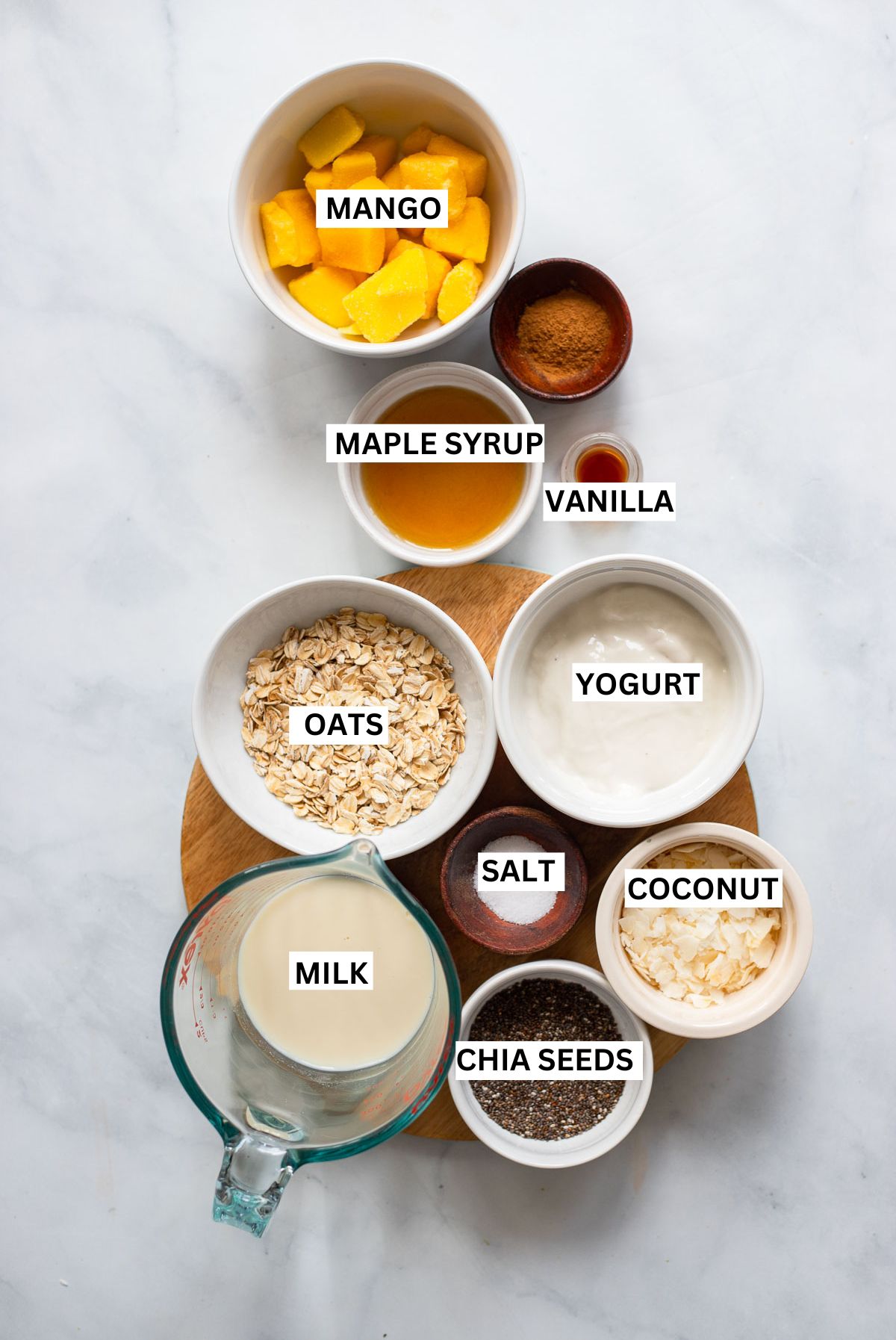 mango overnight oats ingredients in small bowls with text overlay labels.