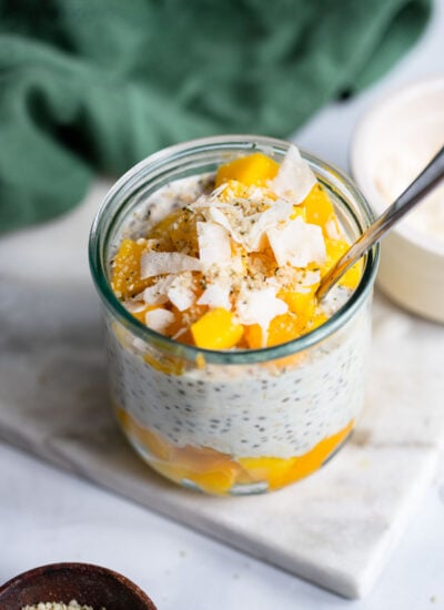 mango overnight oats in a glass topped with mango and coconut flakes.