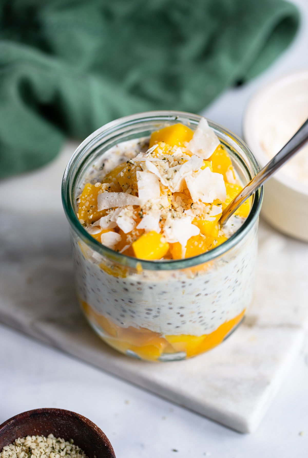 mango overnight oats in a glass garnished with coconut flakes.