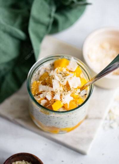 vegan mango overnight oats in a glass with a spoon.