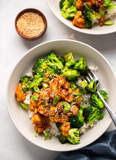 sticky tempeh in bowl with rice and broccoli topped with green onion.