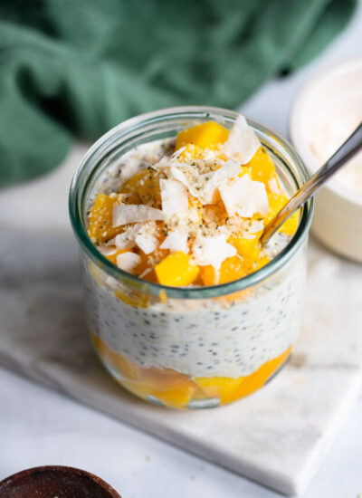 mango overnight oats in a glass garnished with coconut flakes.