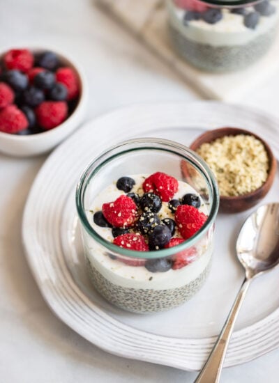 chia seed pudding in a glass jar topped with yogurt and fresh berries. 