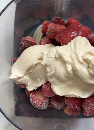 food processor with frozen strawberries and yogurt added.
