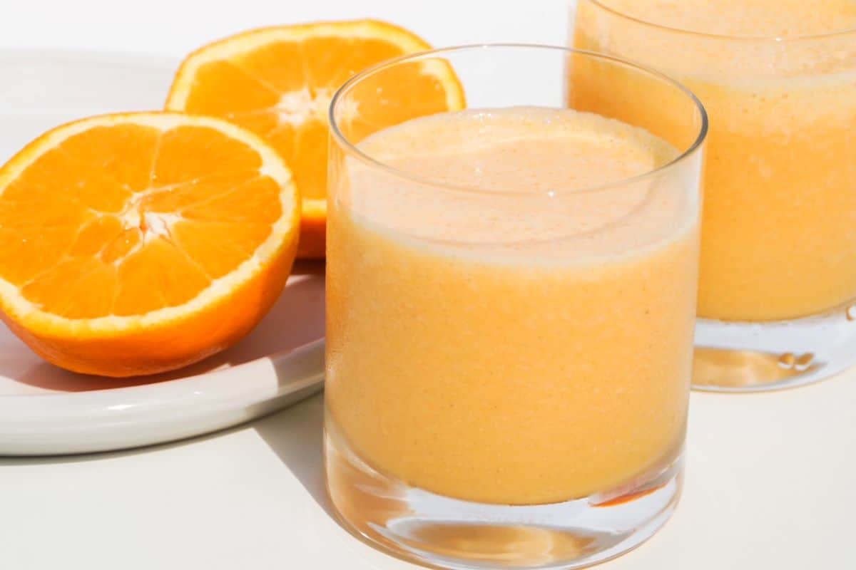 orange carrot oat milk smoothie in a short glass.