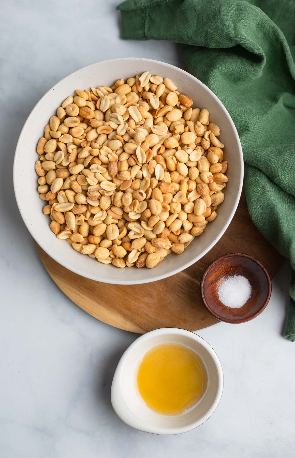 homemade peanut butter ingredients in bowls on a white background.