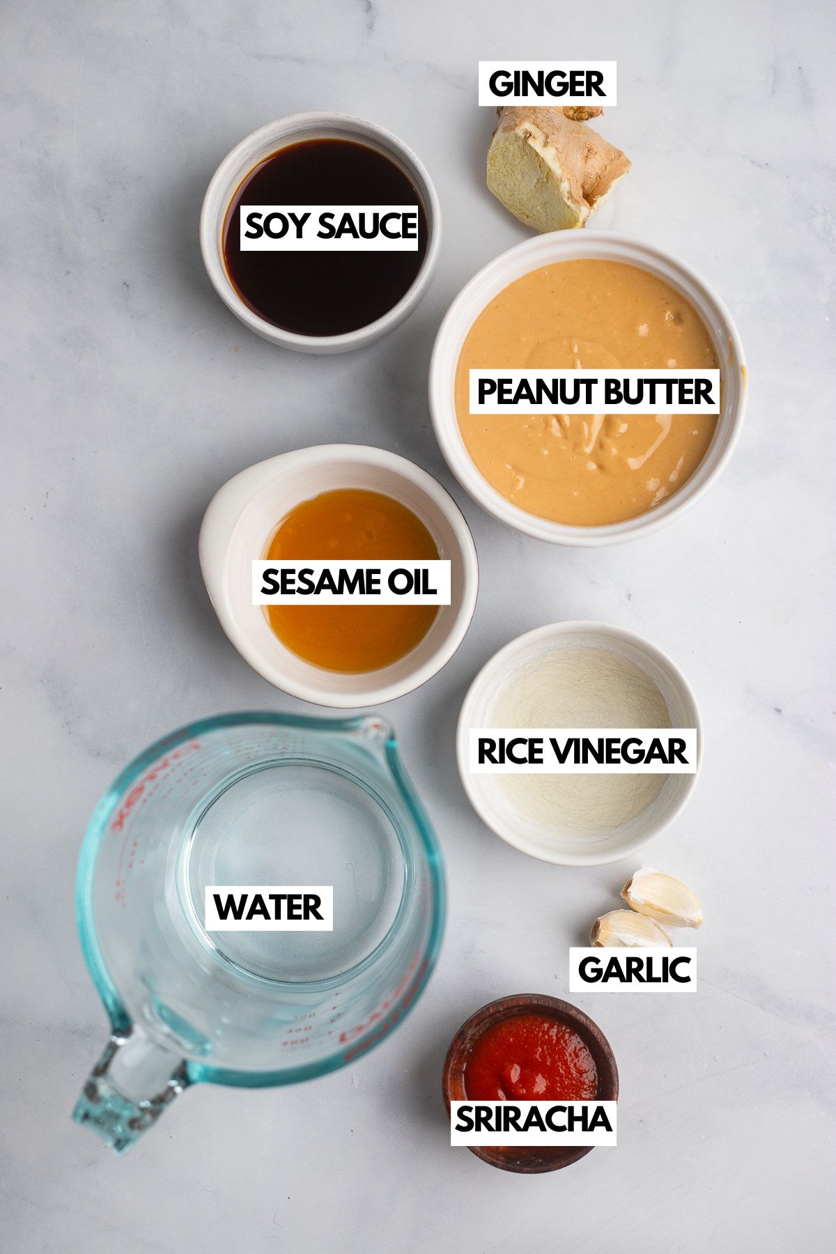 peanut butter stir fry sauce ingredients in small bowls on a white background. 