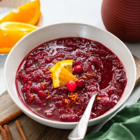 cranberry sauce in serving bowl garnished with orange wedges.