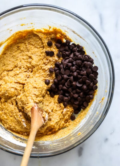 vegan pumpkin muffin batter in a bowl with a wooden spoon.