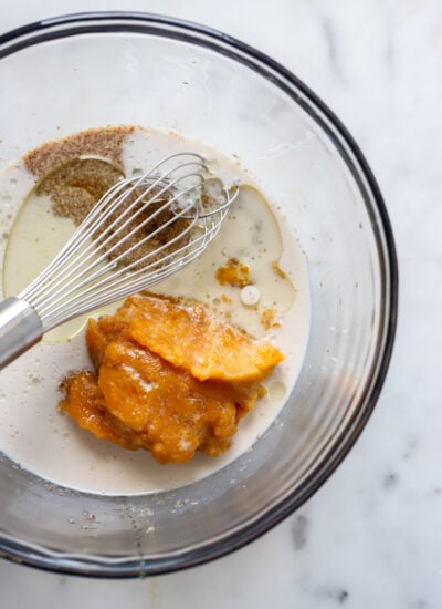 wet ingredients for pumpkin muffins in a bowl with a whisk.