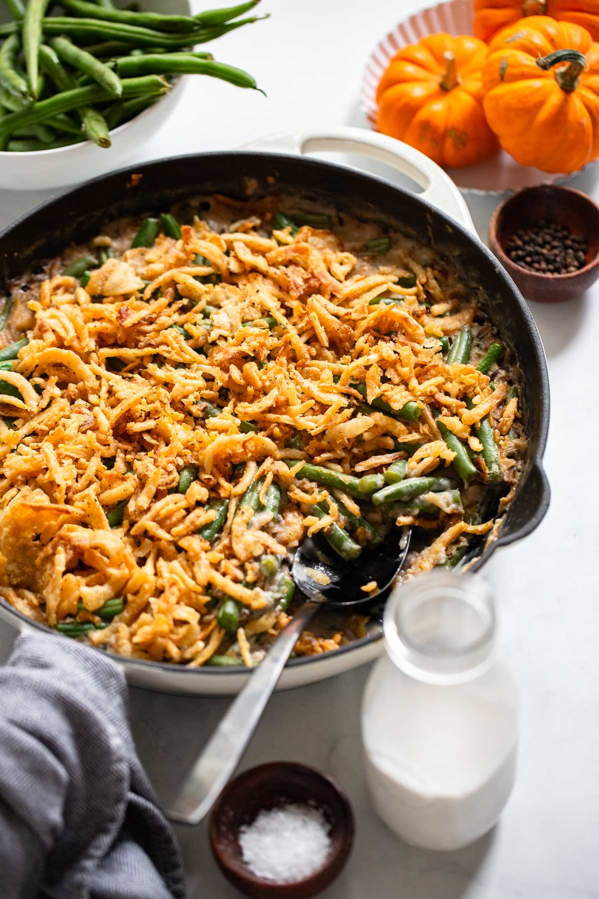 vegan green bean casserole in a white skillet with a serving spoon.