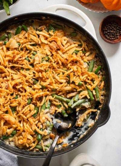 vegan green bean casserole in a skillet with a serving spoon.