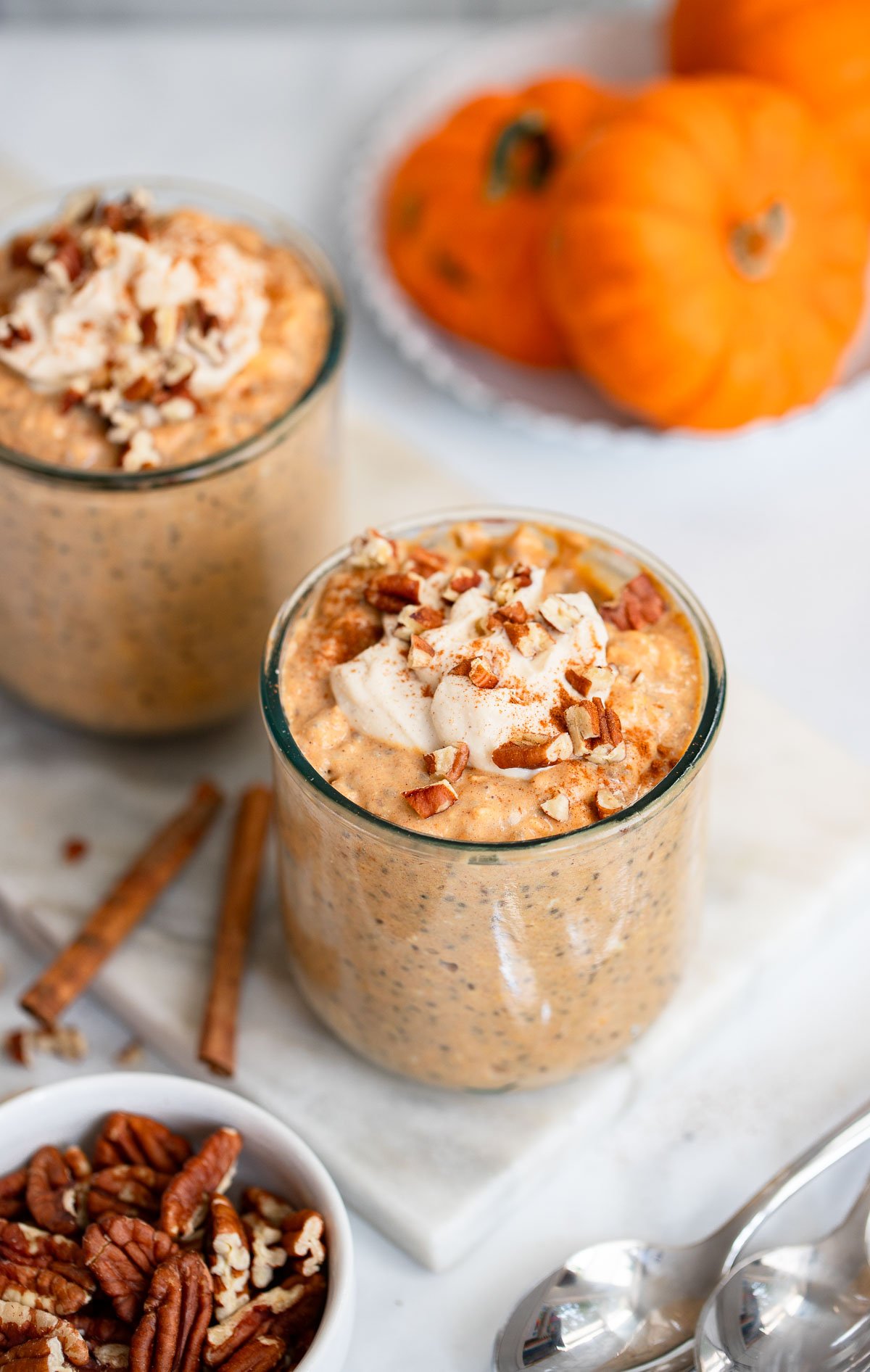 pumpkin pie overnight oats in a glass topped with yogurt and chopped pecans.