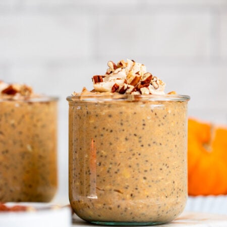 pumpkin pie overnight oats in a glass jar topped with chopped pecans.