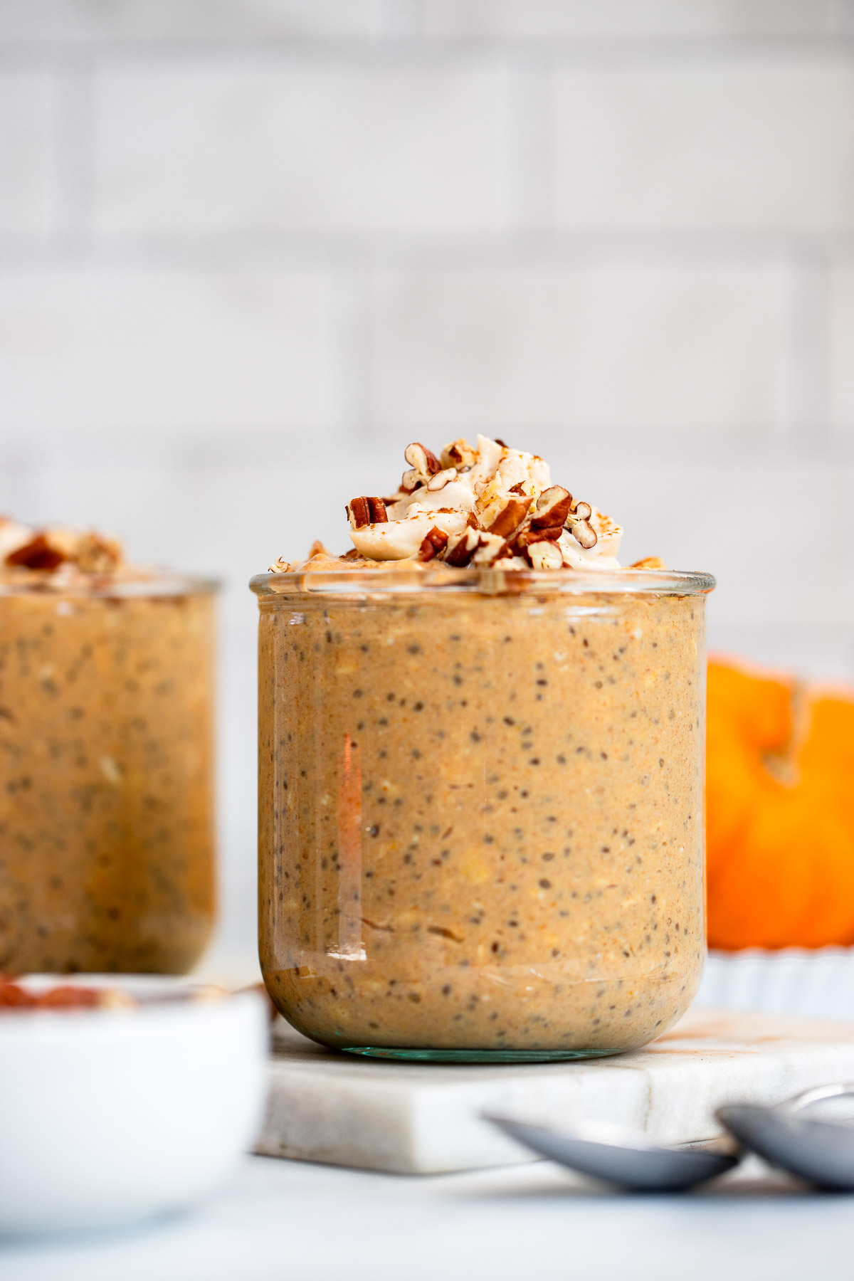 pumpkin pie overnight oats in a glass jar topped with chopped pecans.