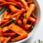 roasted carrots with thyme in a white serving bowl.