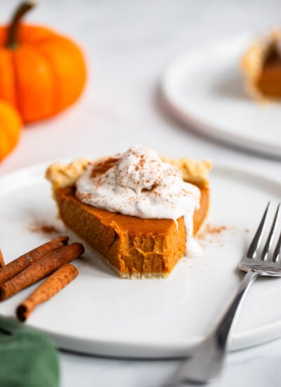 slice of vegan pumpkin pie on a plate topped with whipped cream.