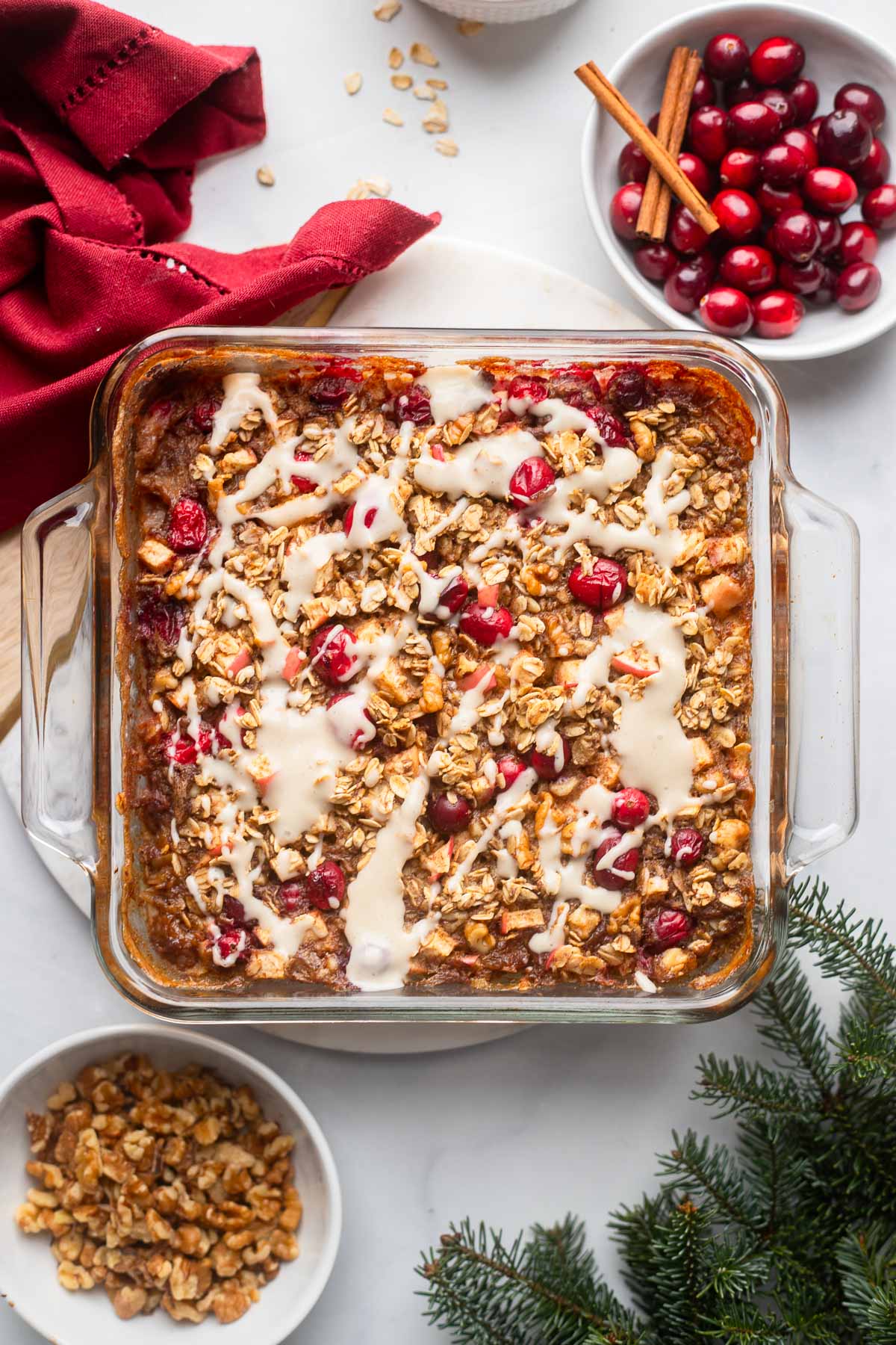 cranberry baked oatmeal in a square baking dish topped with yogurt sauce.