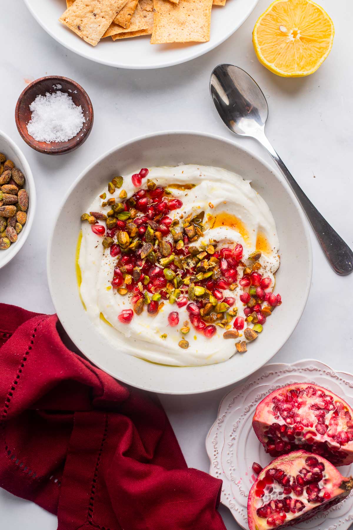 vegan whipped feta dip in a serving bowl topped with chopped pistachios and pomegranate. 