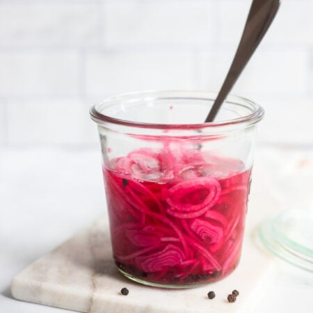 quick pickled red onions in a jar with a fork.