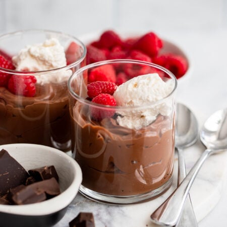 vegan chocolate mousse in a glass with whipped cream and fresh raspberries.
