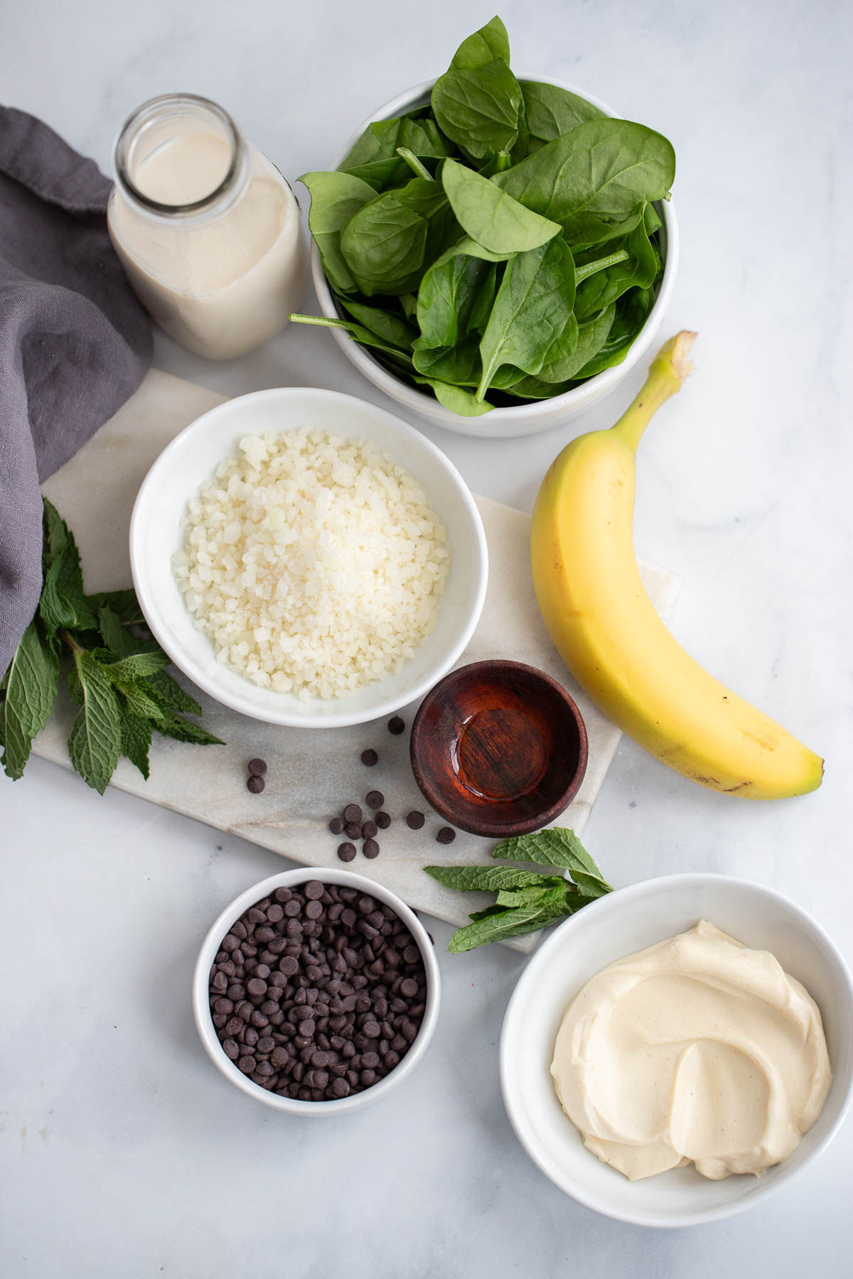 mint smoothie ingredients in small bowls on a white background. 